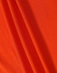 A close-up of orange fabric featuring a textured surface, ideal for polo shirts. The image includes a logo.