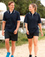 A navy unisex polo shirt with contrasting white trim, worn by a man and woman walking outdoors.