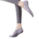 A pair of grey yoga socks with grip dots, worn on a foot, displayed alongside grey leggings.