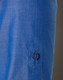 A close-up of a blue women's shirt featuring a button and a rolled-up sleeve. The fabric has a subtle texture.