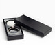 A silver keychain displayed in a black gift box, featuring a sleek design and a glossy finish.
