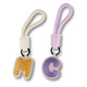 Two bag charms in pastel colours: one yellow 'M' and one purple 'C', each with a detachable strap.