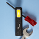 A rechargeable work light in black with a yellow light panel, alongside a red screwdriver and a silver wrench.