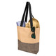 A beige and black tote bag with black straps, containing a towel and a straw hat, and sunglasses resting on the bag.