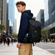 A young person wearing a navy hoodie stands outdoors with a black packable travel backpack and a drink bottle attached.
