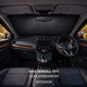 A car interior featuring a black reflective sunshade across the windshield, with leather seats and wooden accents.