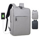 A grey backpack with a front pocket, featuring a USB charging port and black straps, with a logo on the side.
