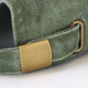 A close-up of a green vintage washed cap featuring a metal adjuster on the strap.