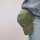 A vintage washed cap in green with a logo, resting against denim jeans.
