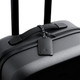 A black suitcase featuring a sleek leather luggage tag with a braided attachment. It has a minimalist design and a logo.