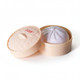 A squishy bun in a round, light peach container with a lid, featuring a soft purple bun inside.