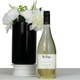 A bottle of white Sauvignon Blanc wine beside a black vase with white flowers. The bottle has a label and branding.