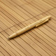 A bamboo pen with a natural finish, featuring a clip and branding. The background is made of bamboo material.