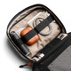 A tech kit featuring a grey exterior, tan interior, drink bottle, earphones, charging cables, and a pen.