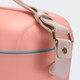 A peach cooler bag with a light pink shoulder strap and a blue zip. It features a branded logo on the side.
