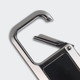 A silver metal carabiner with a curved hook and a small, detailed closure mechanism. It features a logo on one side.