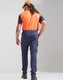 A man wearing orange and black work attire stands with his back to the camera, sporting navy blue flexi work pants and a helmet.