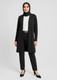 A longline cardigan in black, paired with a white blouse and black trousers, worn by a woman in a hijab.