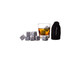 A drink glass filled with whisky and ice cubes, alongside a bag containing whisky rocks. The rocks are grey in colour.