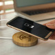 A bamboo wireless charger with a smartphone being placed on it, featuring a charging indicator on the phone's screen. A bamboo wireless charger with a smartphone being placed on it, featuring a charging indicator on the phone's screen.