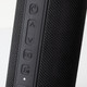 A black Bluetooth speaker featuring textured material and control buttons on the side. Contains a branding logo.