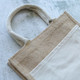 A jute tote bag featuring a natural and cream colour scheme with sturdy handles and a simple design. A jute tote bag featuring a natural and cream colour scheme with sturdy handles and a simple design.