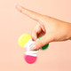 A hand spins a multi-coloured highlighter with pink, yellow, green, and orange caps against a peach background.