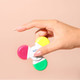 A hand holding a Fiddle Spinner Highlighter featuring pink, yellow, green, and white sections with a logo.