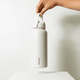 A drink bottle with a sleek white design and a handle, featuring a logo on its side.
