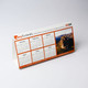 A desk calendar featuring a white and orange design with months displayed from January to June, including a scenic image. A desk calendar featuring a white and orange design with months displayed from January to June, including a scenic image.