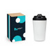 A reusable coffee cup in white with a black lid, accompanied by a branded box featuring a logo and abstract design.