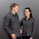 A men's long sleeve button-up shirt in dark grey, featuring a logo and styled on a male and female model.