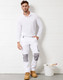White unisex cargo work pants with grey accents, paired with a long-sleeve white top and work boots, standing next to a paint bucket.