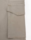 A close-up of a beige work pant pocket featuring a flap, showcasing the fabric texture and stitching detail.