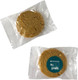A round, light brown cookie packaged in clear plastic, featuring a logo on the front.