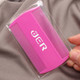 A pink pet flea comb in a clear packaging held by a hand, featuring a logo.