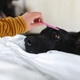 A pink pet flea comb is being used on a black dog lying on a white blanket.