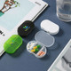 Three pill boxes in green, black, and white, displaying various pills inside a transparent compartment.