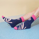 Woven socks in navy blue with pink accents and a leaf pattern, featuring a logo on the side.