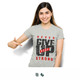 A woman wearing a grey T-shirt with motivational text and a logo, pointing towards the shirt. A woman wearing a grey T-shirt with motivational text and a logo, pointing towards the shirt.