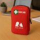 A red first aid kit with a zippered closure, featuring a logo and a green cross symbol.