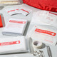 A red first aid kit containing various items, including an emergency blanket, adhesive strips, triangular bandages, and more. A red first aid kit containing various items, including an emergency blanket, adhesive strips, triangular bandages, and more.