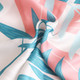 A silk chiffon scarf featuring a vibrant design with pink and blue tropical leaves on a white background.