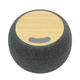 A round, charcoal grey wireless speaker with a bamboo top and a simple control panel. Branding appears on the speaker.