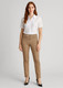 A woman stands wearing slim leg stretch chino pants in tan and a white collared shirt, paired with heels. A woman stands wearing slim leg stretch chino pants in tan and a white collared shirt, paired with heels.