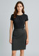 A woman stands wearing a black top and a dark grey pencil skirt. The skirt features a sleek design and a waistband.