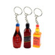 Three colourful resin keychains shaped like drink bottles, featuring red, amber, and black designs with keyring attachments.
