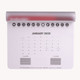 A mouse mat in white with a 2025 calendar layout, featuring a grey edge and icons across the top.