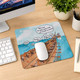 A colourful mouse pad featuring an illustrated scene of a beach with people interacting, along with a logo.