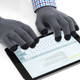 Grey gloves with black tips are worn while typing on a tablet device. The hands are positioned over the screen.